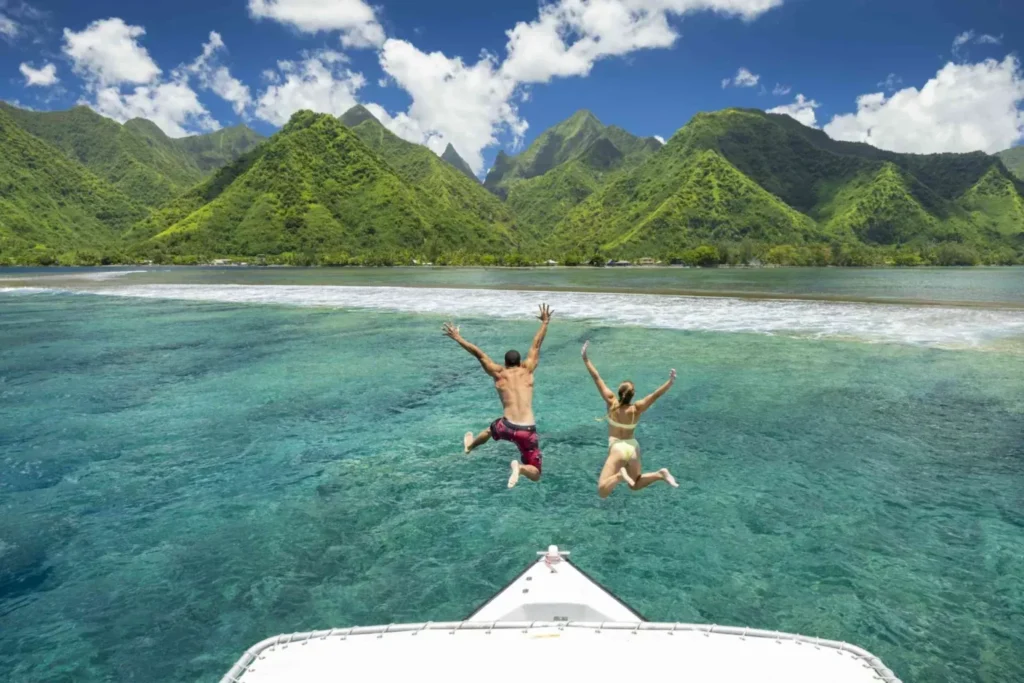 A snorkeler swimming with blacktip reef sharks and stingrays in the shallow waters of Bora Bora.